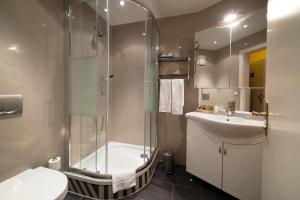 a bathroom with a shower and a sink and a toilet at Atlas Grand Hotel in Garmisch-Partenkirchen +61 photos