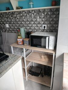 a microwave on a shelf in a kitchen at Macarena-al in Almada +14 photos