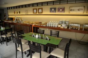 a restaurant with green tables and chairs and a bar at Hotel São Domingos in Feira de Santana