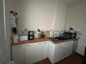 a kitchen with white cabinets and a counter top at Logement Salbris sologne in Salbris +2 photos