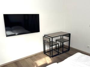 ビーレフェルトにあるModern studio for 2 - Central I Parking I WiFiのテーブル2台と壁掛けテレビ付きの部屋