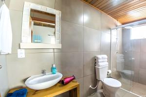 Un baño con lavabo, inodoro y espejo. en Java Bangalôs, en Imbituba