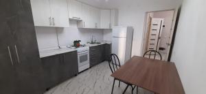 a kitchen with white cabinets and a table with chairs at Квартира in Tridtsatʼ Let Kazakhstana +6 photos