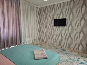 a bedroom with a bed with a television on the wall at Квартира in Tridtsatʼ Let Kazakhstana