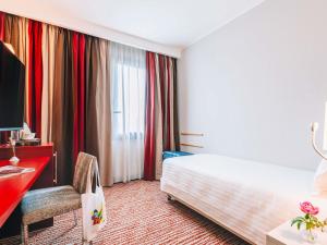 a hotel room with a bed and a desk and a window at Mercure Roma Piazza Bologna in Rome