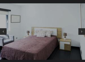 a bedroom with a large bed and a chair at La Perla in Fermentelos +8 photos