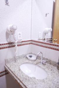 a bathroom counter with a sink and a phone at Castelo Inn Hotel in Goiânia