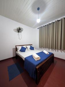 a bedroom with a bed with blue sheets and a window at Sea Breeze Rest in Talalla South