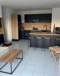 a kitchen with black cabinets and a white tile floor at Appartement proche mer in Le Muy