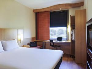 a hotel room with a bed and a desk with a laptop at Ibis Barcelona Mollet in Mollet del Vallès