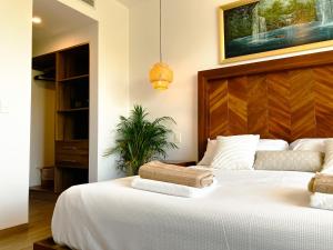 a bedroom with a large white bed with a wooden headboard at Stylish Playacar Condo with Balcony & Pool in Playa del Carmen +36 photos
