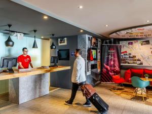 a man with a suitcase walking past a counter in a store at Ibis Bilbao Barakaldo in Barakaldo