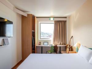 a hotel room with a bed and a desk and a window at Ibis Bilbao Barakaldo in Barakaldo