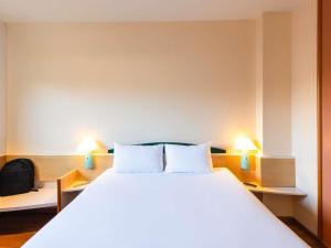 a bedroom with a large white bed with two lamps at Ibis Bilbao Barakaldo in Barakaldo +72 photos