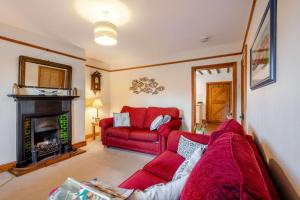 a living room with a red couch and a fireplace at China Cottage in Weybourne