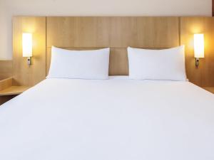 Una cama blanca grande con dos almohadas en una habitación. en Ibis Madrid Calle Alcalá, en Madrid