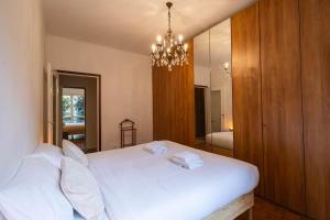 ein Schlafzimmer mit einem weißen Bett und einem Kronleuchter in der Unterkunft Homing - Prestinari 15 in Mailand + 7 Fotos