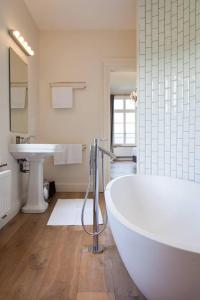 a white bathroom with a tub and a sink at Château Charles in Pepinster