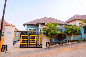 a blue house with a yellow gate and palm trees at Modern Furnished House in Kabeza in Kigali