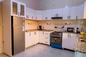 a kitchen with white cabinets and a stainless steel refrigerator at Modern Furnished House in Kabeza in Kigali +15 photos