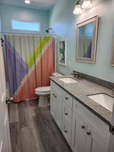 ein Badezimmer mit zwei Waschbecken und einem Regenbogen-Duschvorhang in der Unterkunft Escape to the beach with pets &kids in Bolivar Peninsula