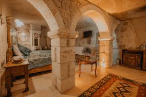 a bedroom with a bed and a table in it at Serenus Cave Suites in Ortahisar