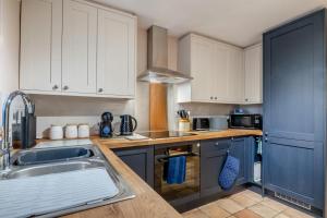 une cuisine avec des armoires blanches et un évier dans l'établissement Blacksmiths Cottage - Buxton Norfolk, à Buxton 7 autres photos