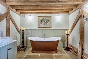 un bagno con una grande vasca e un lavandino di The Hayloft at Ryes Farm a Crowfield