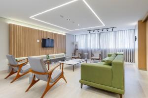 ein Wohnzimmer mit einem grünen Sofa und Stühlen in der Unterkunft Handy Paraíso condomínio com piscina ao lado do Ibirapuera in São Paulo