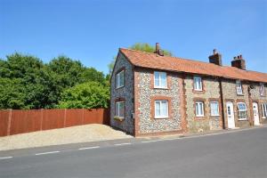 una casa di mattoni sul lato di una strada di Owl Cottage a Holt