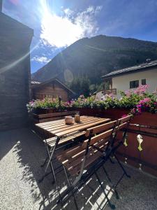 a wooden table and bench on a patio with flowers at Mountaindreams, Wallis, near Saas-Fee, SKi, near Mattmark in Saas-Almagell