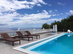 a swimming pool on a balcony with chairs and the ocean at Golden View Residence in Dhërmi