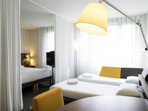 a hotel room with two beds and a lamp at Novotel Suites Paris CDG Airport Villepinte in Roissy-en-France +87 photos