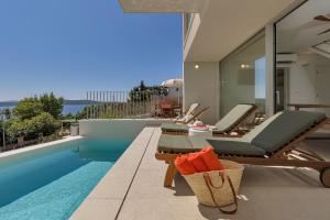 een zwembad met 2 ligstoelen naast een huis bij Vista Divina - Semi Detached Vacation Homes by Irundo in Zavala