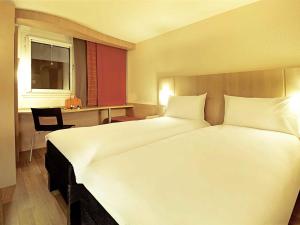 a bedroom with a large white bed and a desk at ibis Porto Centro São Bento in Porto +103 photos