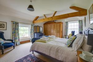 a bedroom with a bed and a chair and windows at St Lawrence House in Harpley