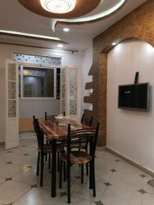 a dining room with a wooden table and chairs at Appt F4 equipé au rez de chaussé d'un immeuble privé in Skikda +9 photos