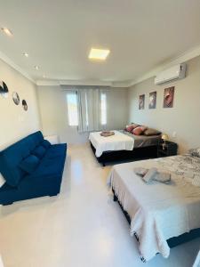 a living room with two beds and a blue couch at Casa de praia SANTINHO in Búzios