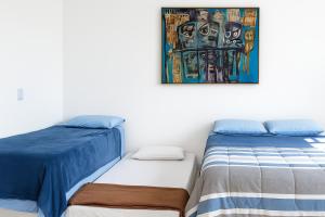a bedroom with two beds and a painting on the wall at Apto no Menino Deus in Porto Alegre
