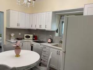 a kitchen with white cabinets and a table with a vase on it at Niki's Dream House in Ierapetra