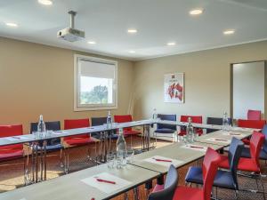 a conference room with tables and red chairs at Ibis Częstochowa in Częstochowa