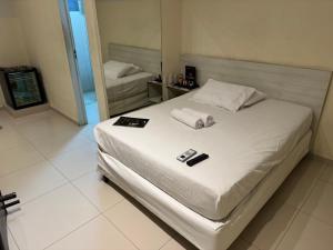 a bedroom with a white bed with towels on it at D'lazer Motel in Caruaru