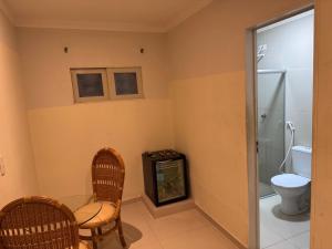 a bathroom with a toilet and a table and chairs at D'lazer Motel in Caruaru