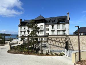 トレブールダンにあるLE TAUREAU T3 Trebeurden acces plage piscine et vue merの黒い屋根の大きな白い建物