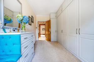 a bathroom with white cabinets and a vase of blue flowers at The Old Vicarage in Truro