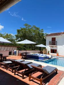 a swimming pool with chairs and umbrellas next to a swimming pool at Hotel Victoria Barichara in Barichara