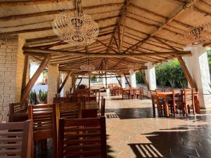 a restaurant with wooden tables and chairs and chandeliers at Hotel Victoria Barichara in Barichara