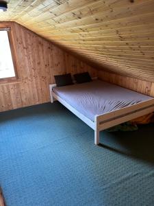 a bed in a cabin with a wooden ceiling at Bokodi üdülő és horgászházak in Oroszlány