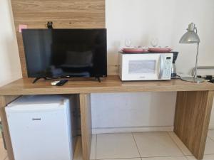 a microwave and a television on a wooden table at Rio Centro Stay 1 in Rio de Janeiro