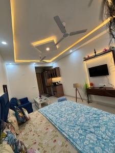 a bedroom with a bed and a flat screen tv at Premium Studio Apartment near Gaur City Mall, Noida Extension in Ghaziabad